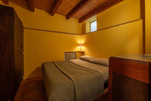- une chambre avec un lit dans une pièce jaune dans l'établissement Relais Castel d'Emilio - Casa VERDE, à Cassero