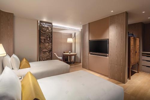 a hotel room with two beds and a television at Waldorf Astoria Bangkok in Bangkok