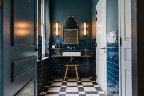een badkamer met blauwe tegels, een wastafel en een kruk bij Hotel Monastère Maastricht in Maastricht