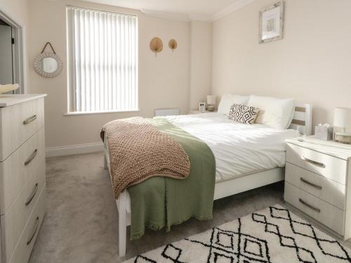 a white bedroom with a bed and a window at 3 Compass Point in Weymouth