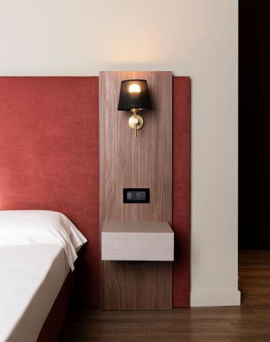 a bedroom with a bed and a lamp on a wall at Mokinba Hotels Montebianco in Milan