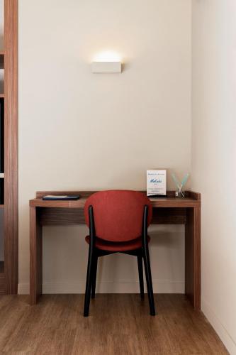 a red chair sitting at a wooden desk at Mokinba Hotels Montebianco in Milan