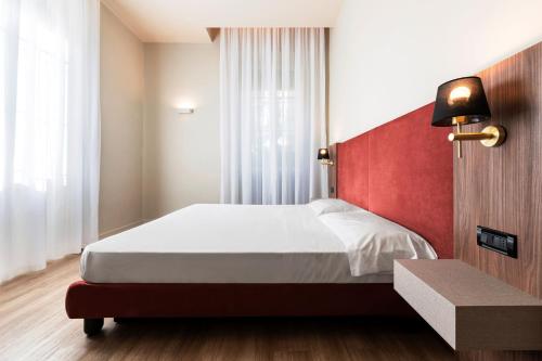 a bedroom with a bed with a red headboard at Mokinba Hotels Montebianco in Milan