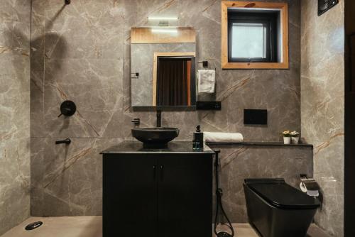 a bathroom with a sink and a toilet and a mirror at Kabins - Homestay Near Pawna Lake, Lonavala in Lonavala