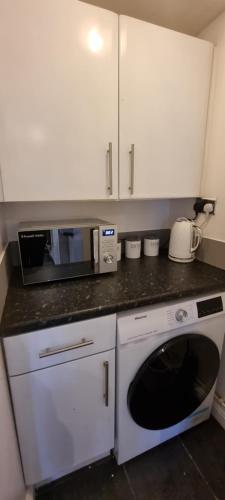 eine Küche mit einer Mikrowelle und einer Waschmaschine in der Unterkunft Silver Serenity in Stoke on Trent