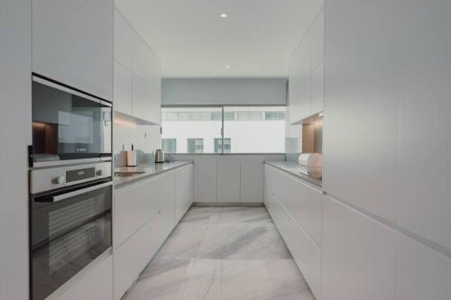 Lux in Porto في بورتو: مطبخ أبيض كبير مع خزائن وأجهزة بيضاء