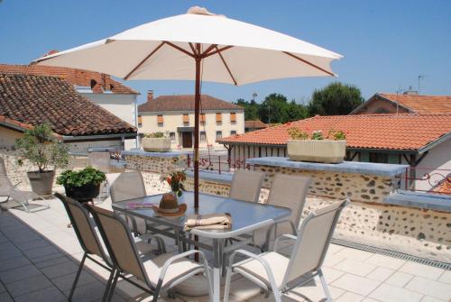 a table and chairs with an umbrella on a patio at Gîte Matran in Cauna