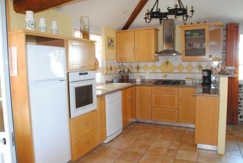a kitchen with wooden cabinets and a white refrigerator at Gîte Matran in Cauna