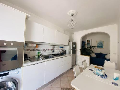 una cucina con armadi bianchi, tavolo e lavandino di MARVELOUS SEA VIEW VILLA a Capri