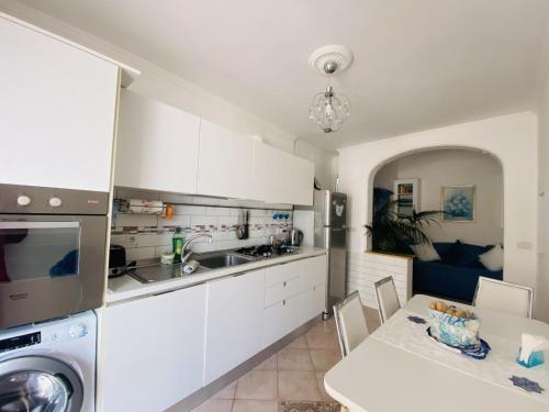 a kitchen with white cabinets and a table and a sink at MARVELOUS SEA VIEW VILLA in Capri