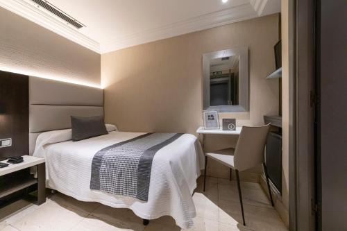 Habitación de hotel con cama, escritorio y espejo. en Hotel Europa, en Pamplona