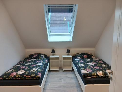 2 Betten in einem kleinen Zimmer mit Fenster in der Unterkunft Neubau: Ferienwohnung Im Suddenfeld - zentral und doch ruhig gelegen in Nordhorn