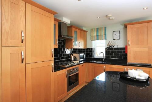een keuken met houten kasten en zwarte aanrechtbladen bij BOURNECOAST-SITUATED NEAR CLIFF TOP & BEACH-FM2872 in Bournemouth