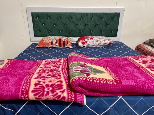 a bed with colorful blankets and pillows on it at GARG COMPLEX GUESTHOUSE in Bharatpur