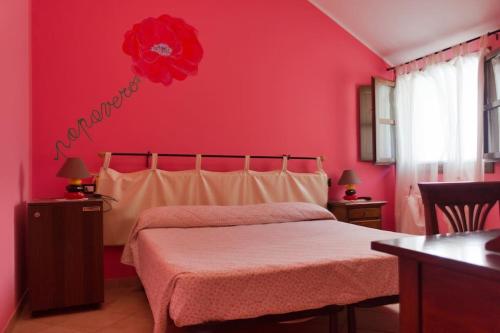 a red bedroom with a bed with a red flower on the wall at Agriturismo a Canonica in Garlenda