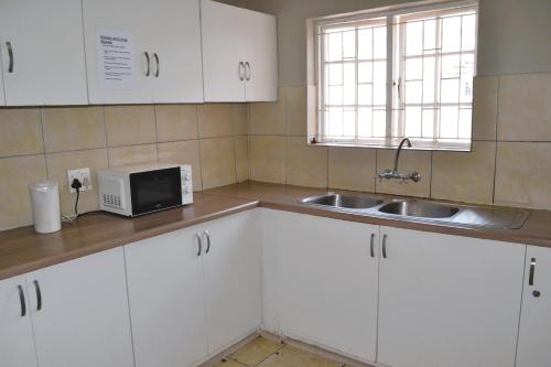 a kitchen with white cabinets and a sink and a microwave at 149 ROCHESTER ROAD. OBSERVATORY in Cape Town