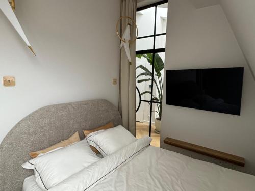 1 cama con 2 almohadas y TV en la pared en URBAN Penthouse FREE parking i rowery, en Poznan