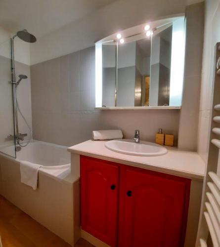 une salle de bain avec une baignoire, un lavabo et un miroir dans l'établissement Praloup 1600 Appartement T4 rénové, à Uvernet