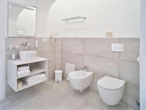 a white bathroom with a toilet and a sink at Hotel Medusa in Finale Ligure