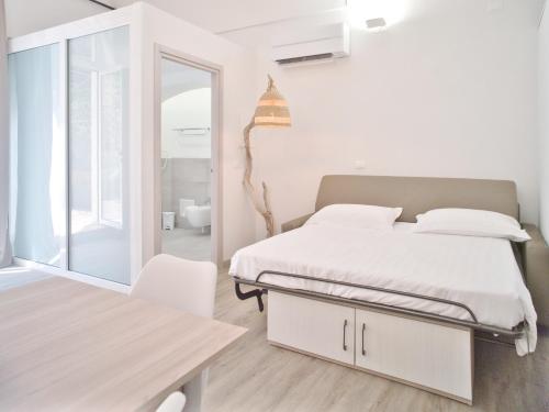 a white bedroom with a bed and a table at Hotel Medusa in Finale Ligure