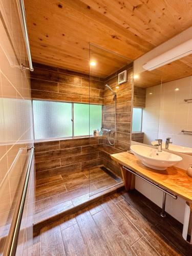 a bathroom with a sink and a glass shower at Snowood Chalet Hakuba in Hakuba