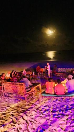 a group of people sitting on a beach at night at Sipano Beach Lodge Kiwengwa in Kiwengwa