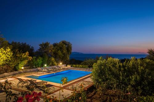 a swimming pool in a backyard at night at Villa Rudi in Trapezaki
