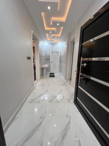 a hallway with a white marble floor and a door at شاليهات توليب in Sabt Alalayah