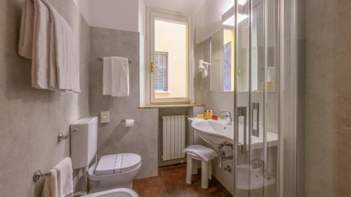 y baño con aseo, lavabo y espejo. en Albergo Reggio, en Reggio Emilia