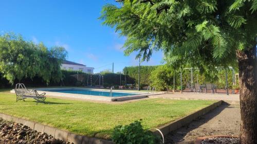 un parque con un banco junto a una piscina en Los Candiles en Cantillana