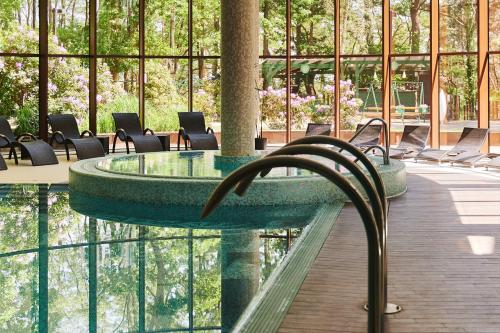 una piscina en un edificio con sillas y mesa en Hotel Narvil Conference & Spa, en Serock