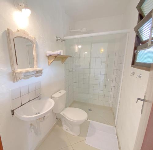 a white bathroom with a toilet and a sink at Pousada Montemar in Ilhabela