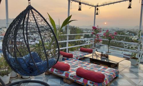 Raahi Backpacker's Hostel في أودايبور: شرفة مع كرسيين مرجوحين وطاولة