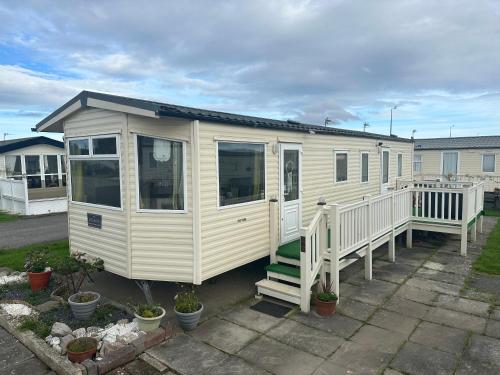 a yellow tiny house with a porch at Robin Hood Rhyl caravan oaklands in Rhyl