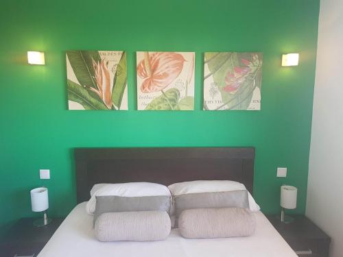 a green wall with four pictures above a bed at BCV - Private 1 Bedroomed Apartment Dunas Resort 3044 and 3077 in Santa Maria