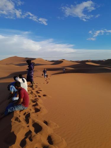 a group of people sitting on the sand in the desert at Auberge chez hammadi in Zagora