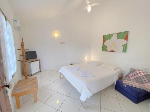 a white room with a bed and a chair at Pousada Montemar in Ilhabela