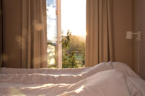 a bed in front of a window with a view at STF Undersvik Gårdshotell & Vandrarhem in Vallsta