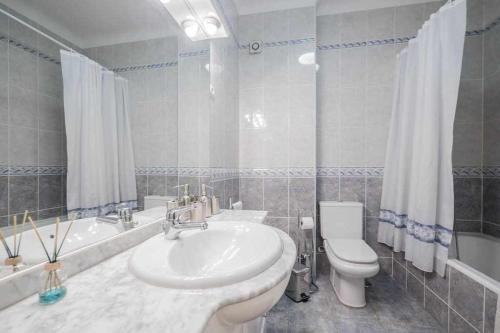 a bathroom with a sink and a toilet and a tub at Apart Lisboa confortavel 2 quartos com terraço in Odivelas