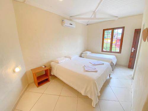 a bedroom with two beds and a table in it at Pousada Montemar in Ilhabela