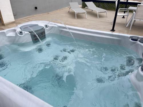 Jacuzzi Penthouse appartement Santa Rosalia Lake & Life Resort Murcia Golf في لوس الكاثاريس: حوض استحمام مليء بالماء مع وجود كرسيين فيه