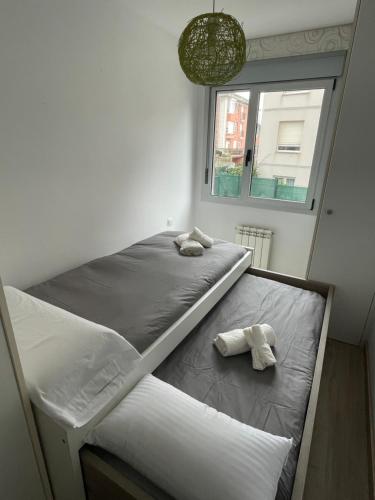two beds in a room with a window at Piso con jardín en Liencres in Liencres