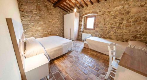 a bedroom with two beds and a stone wall at Abbazia San Pietro in Valle in Vagli