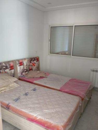 two beds in a room with a window at Zone touristique mahdia en face clinique rahma in Mahdia