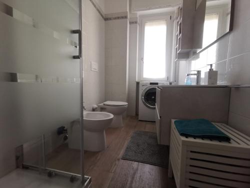a bathroom with a toilet and a sink and a washing machine at Maison - Elegante Casa a pochi minuti dal mare in Quartu SantʼElena