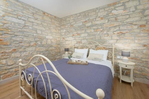 a bedroom with a bed and a stone wall at Villa Onelia by IstriaLux in Vodnjan