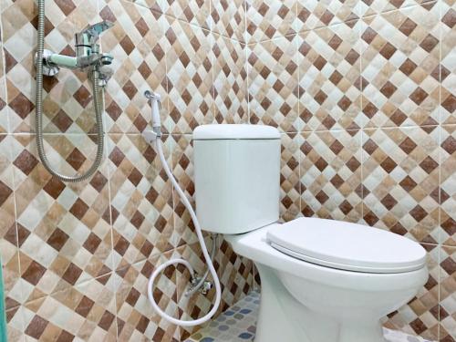 uma casa de banho com um WC e uma parede em mosaico em RedDoorz @ Langkapura Lampung em Kedaton