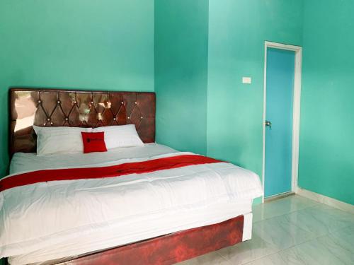 um quarto com uma cama grande e paredes azuis em RedDoorz @ Langkapura Lampung em Kedaton