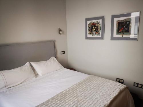 馬拉加的住宿－Apartamento Cervantes，卧室配有一张白色床,墙上挂有两张照片