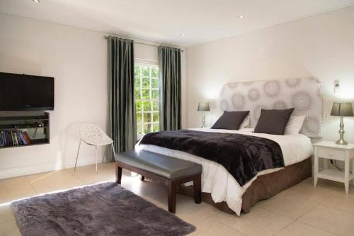 a bedroom with a large bed and a television at Leopard Tree Cottage in Franschhoek
